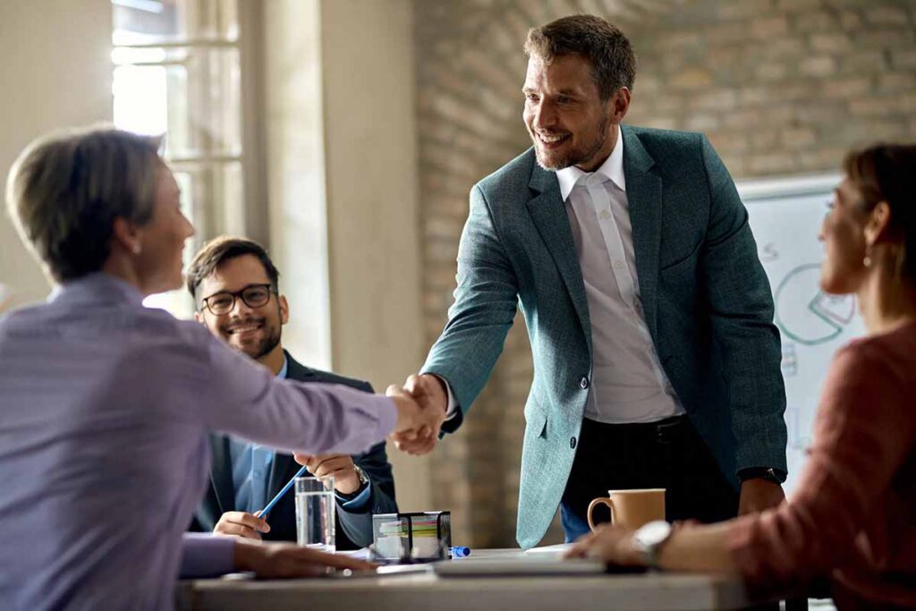business-coworkers-shaking-hands-meeting-office-focus-is-businessman-scaled business coworkers shaking hands meeting office focus is businessman scaled 1